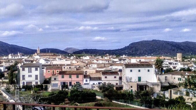 llor Panoramisch uitzicht op het dorp Sant Llorenç des Cardassar op Mallorca, met traditionele huizen op de voorgrond en bergketens op de achtergrond onder een bewolkte lucht.